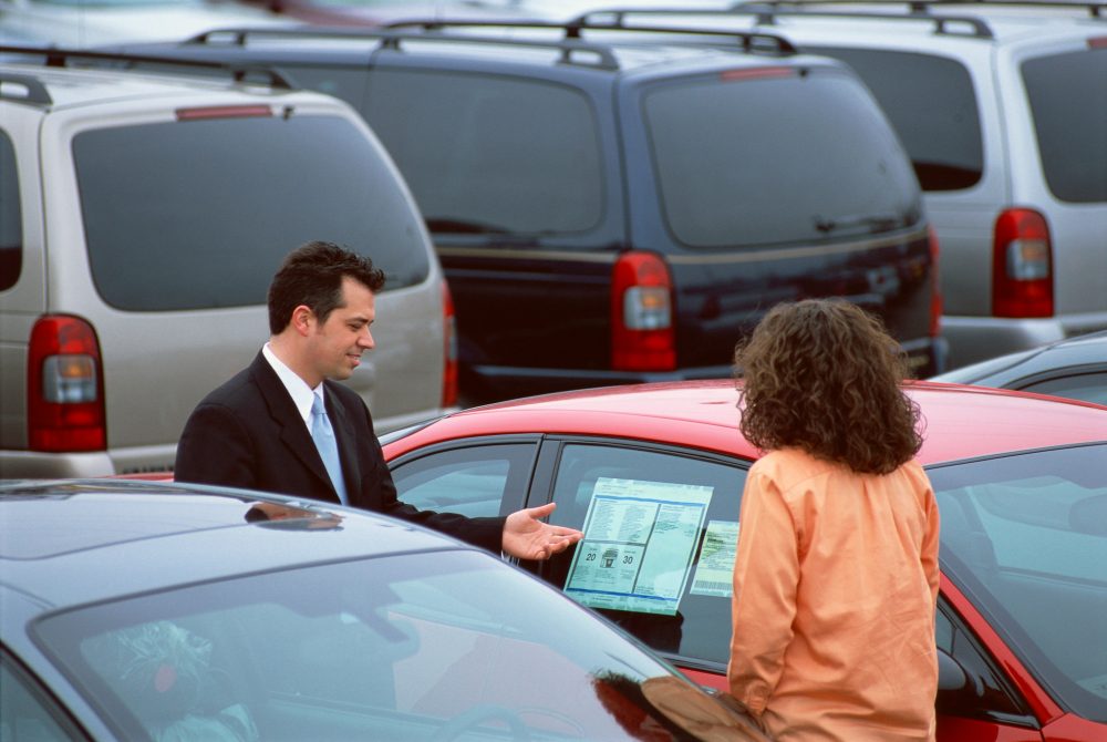 Car salesperson helping someone find a car to buy on a dealership lot