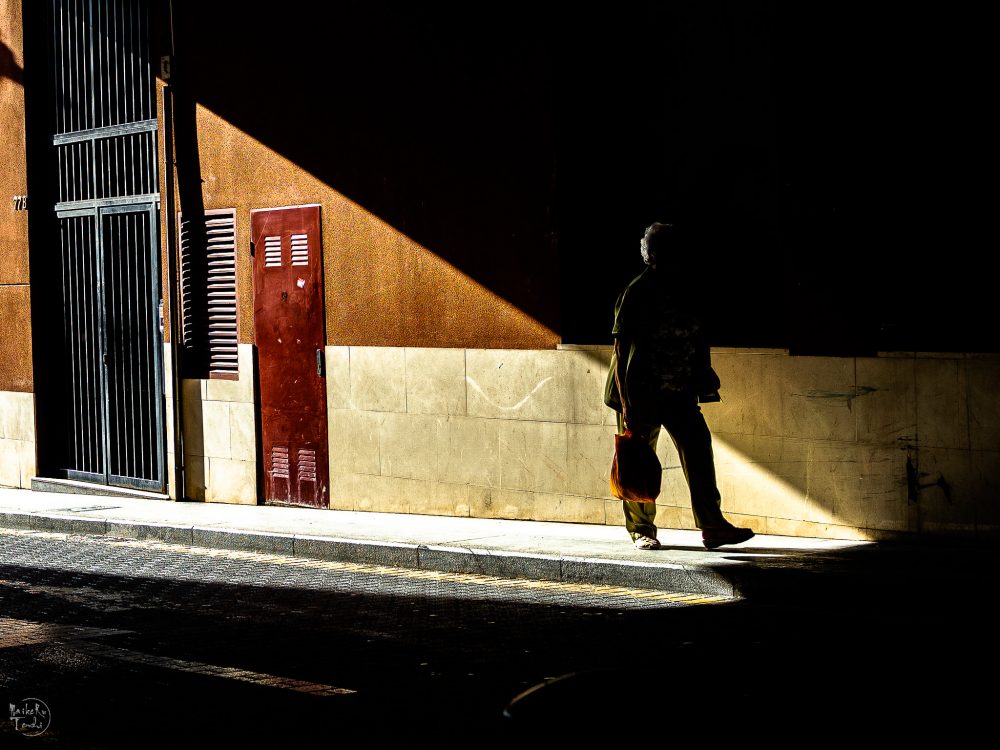 person walking into the shadows on a city street