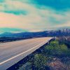 artistic view of the Pacific Coast Highway with mountains in the background and the ocean on the left