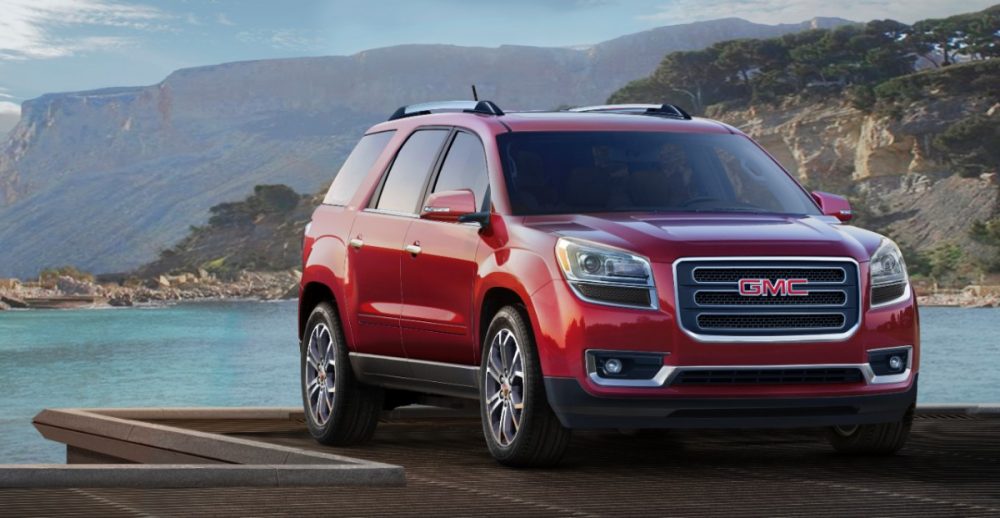 2013 GMC Acadia parked by a lake in a mountain range