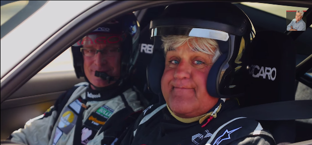 Race car driver Kelly Collins (left) and comedian Jay Leno (right), who's helmet can barely contain his face test driving a Porsche 911