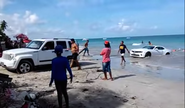 A Jeep Liberty attempts to pull a beached Camaro in this YouTube video