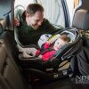 Man strapping child into rear-facing car seat