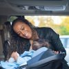 Woman strapping child into rear-facing car seat