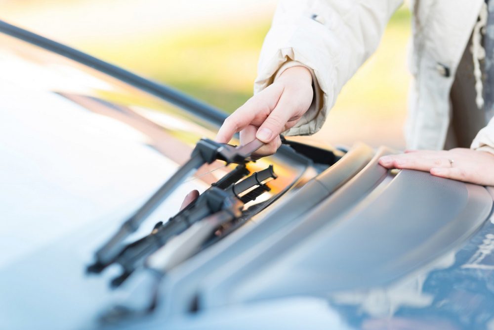 person touching a windshield wiper