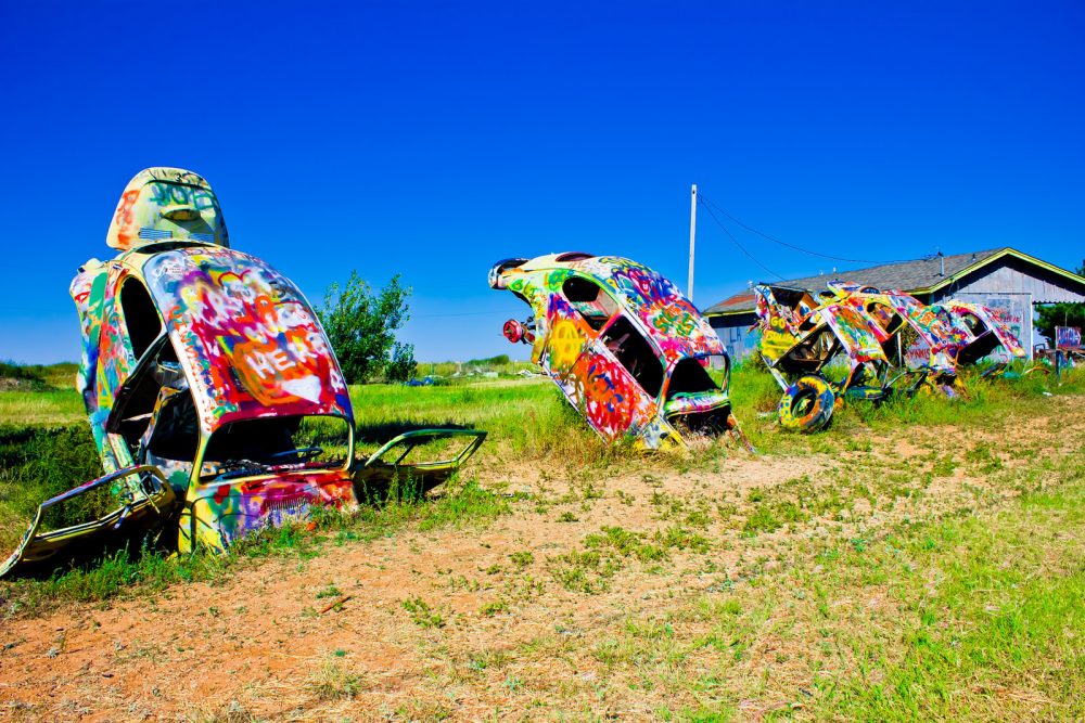 Painted Volkswagen Beetles sticking out of the ground at VW Slug Bug Ranch in Conway, Texas