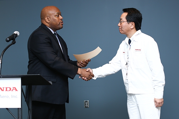 Honda Aero President Atsukuni Waragai accepts the PART 145 repair station certificate from Jeffrey Phipps, manager of the FAA's Flight Standards District Office in Greensboro.