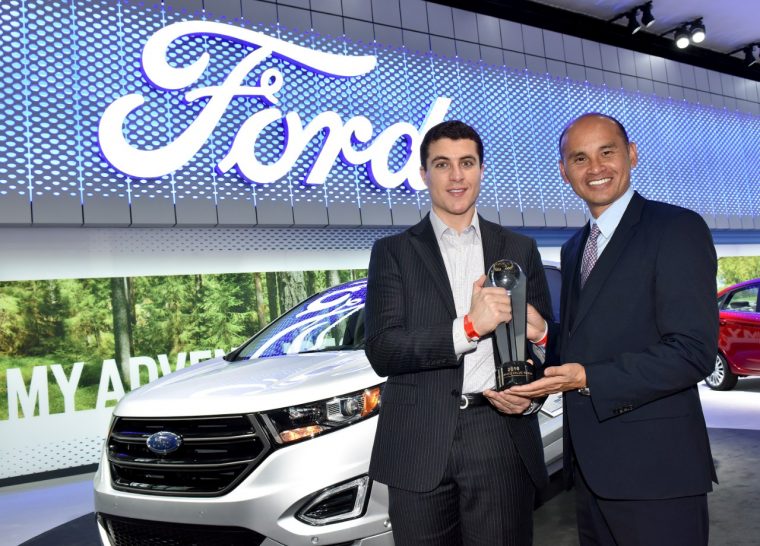  Jim Nguyen (right), TrueCar EVP, hands Ford's Omar Odeh (left) a trophy for the automaker's three wins in the inaugural TrueCar Pre-Owned Value Awards at NYIAS