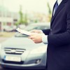 Businessman in suit with clipboard testing car