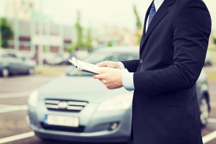 Businessman in suit with clipboard testing car