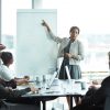 Black woman presenting to team of office executives around table