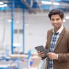 Man in suit with tablet in warehouse boxes