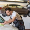 Man mechanic working on cleaning car in garage