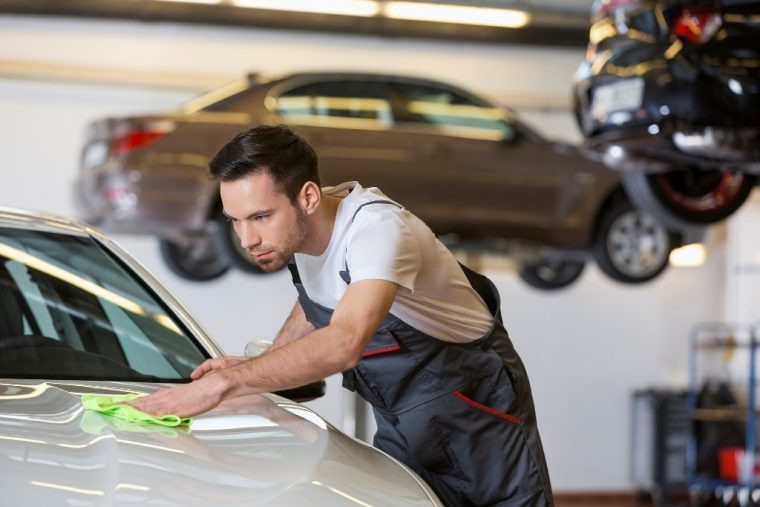 Man mechanic working on cleaning car in garage