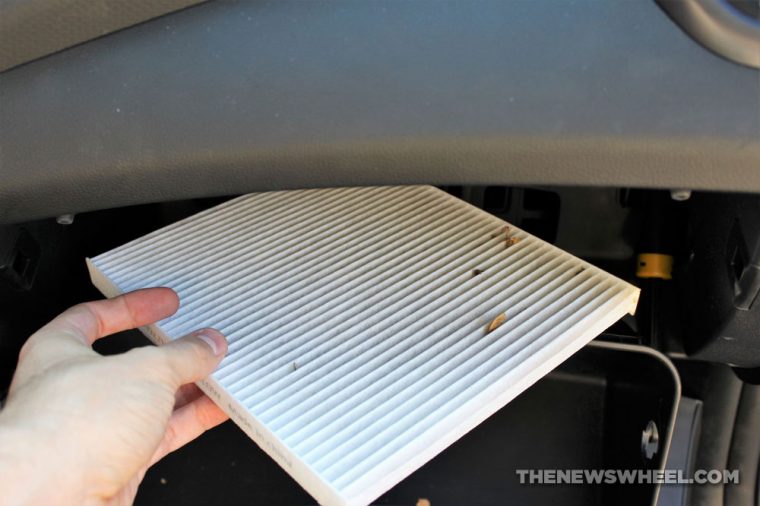 Person changing cabin air filter in a car