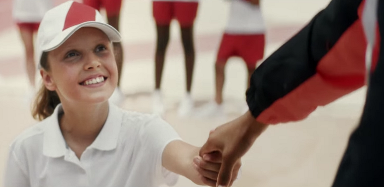 Girl holds medal winner's hand in Toyota ad