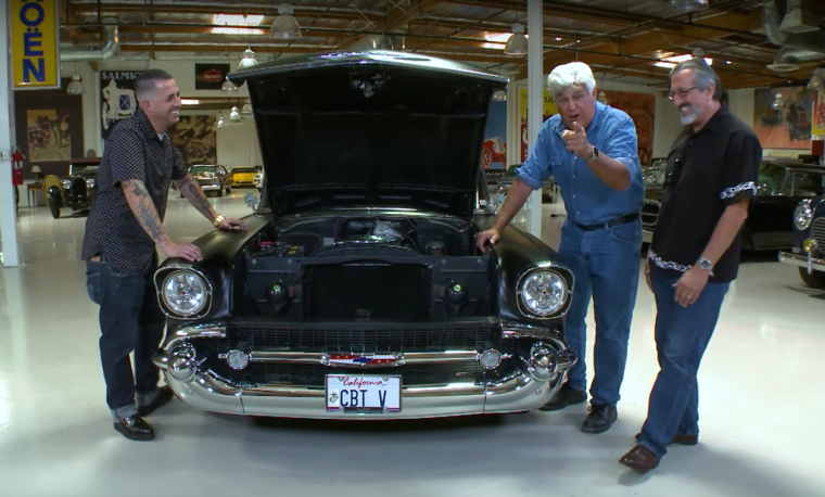 Jay Leno poses with a father and son team of US veterans and the 1957 Chevy 210 that they built together