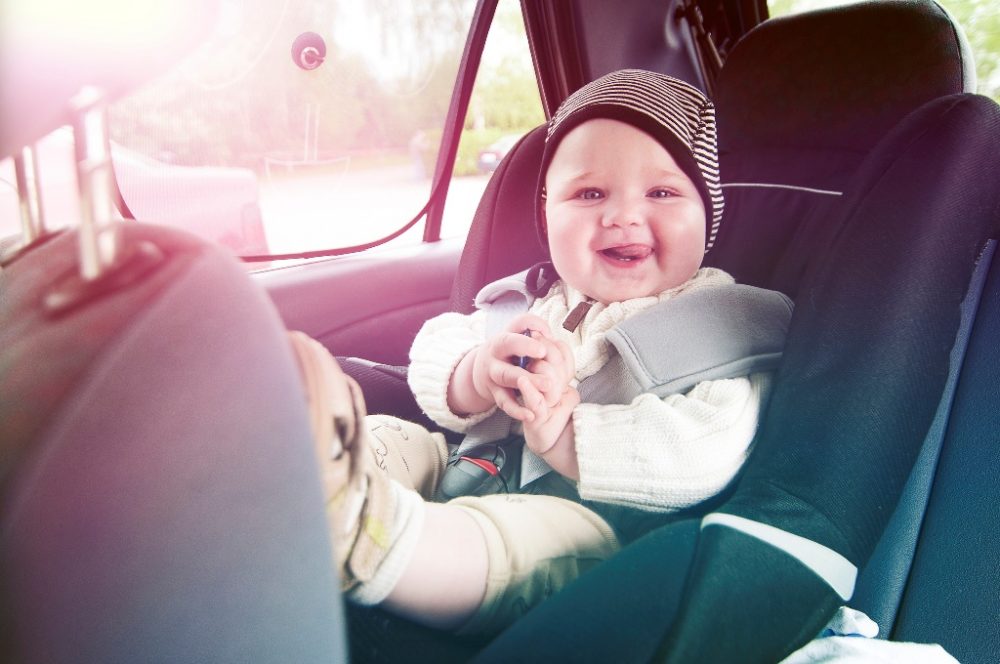 happy baby in car seat with hat