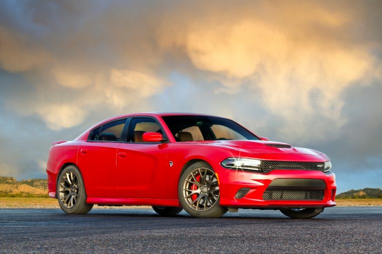 A red Dodge Charger SRT Hellcat sitting on asphalt against an ominous sky