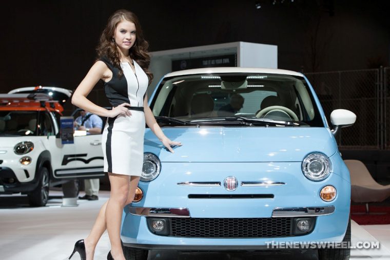 Woman posing beside Fiat 500 at auto show