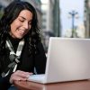 Dark-haired woman looking at her laptop to shop for a car online