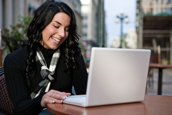 Dark-haired woman looking at her laptop to shop for a car online