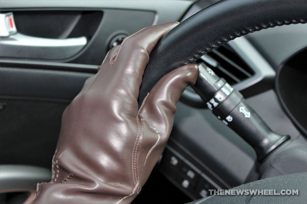 brown leather driving gloves on car steering wheel left hand