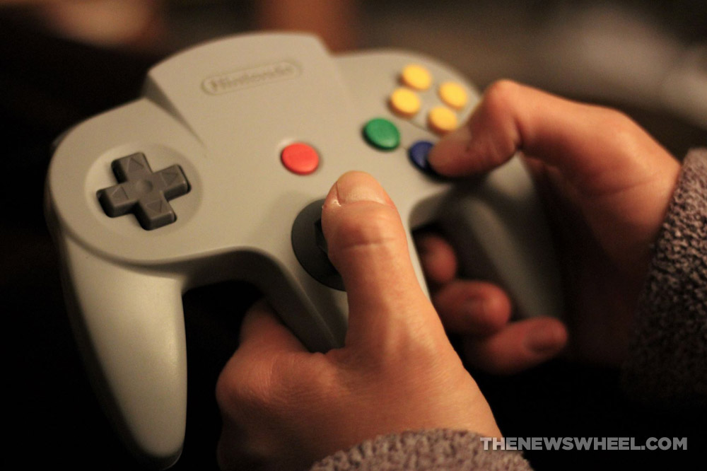 Person holding a video game controller for a Nintendo 64 retro console