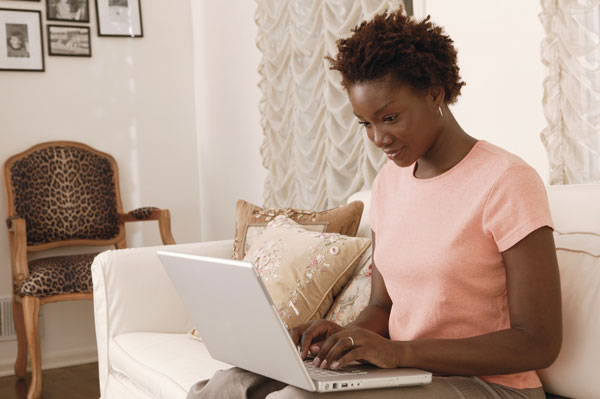 Woman sitting on her couch searching the internet on her laptop.