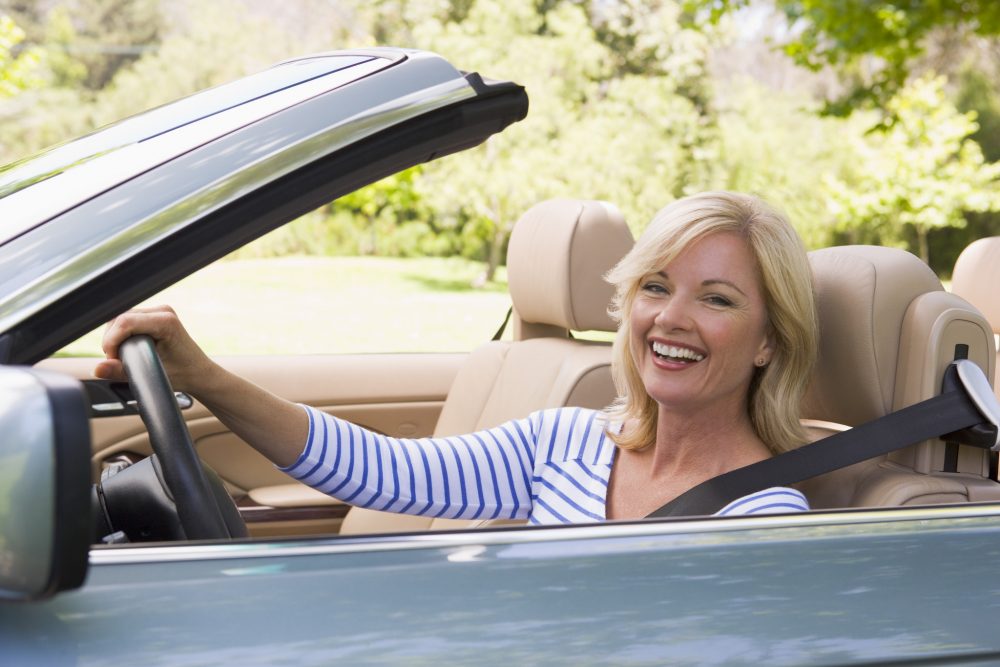 woman driving car convertible healthy happy smiling driver