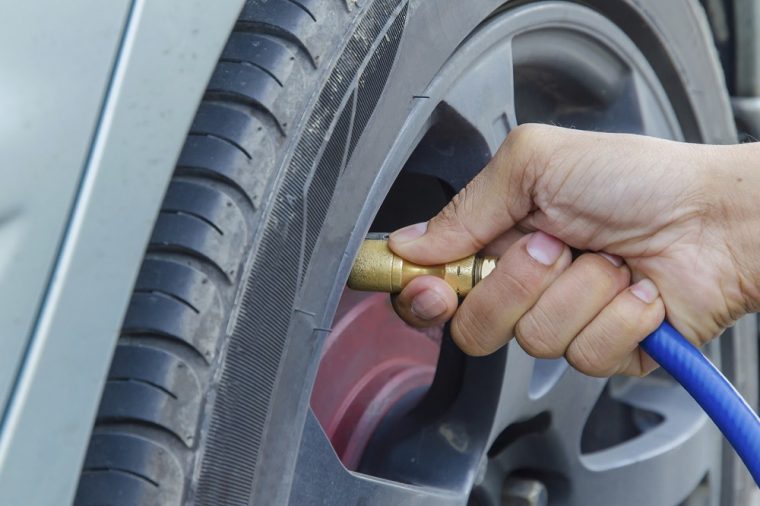 person checking tire pressure on a car