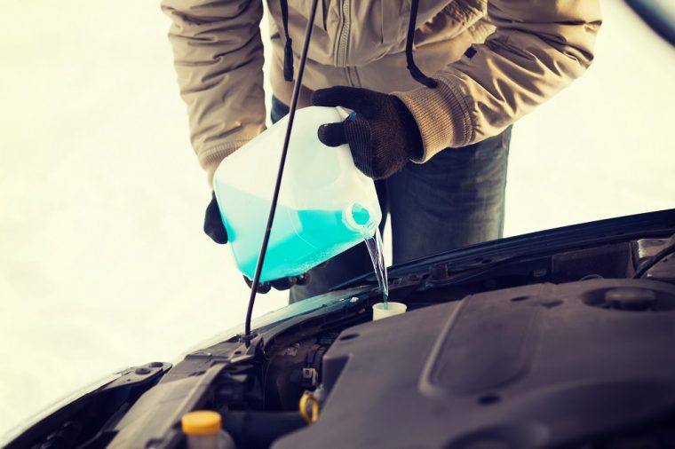 person filling fluids in car