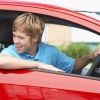 teenage boy driving red car