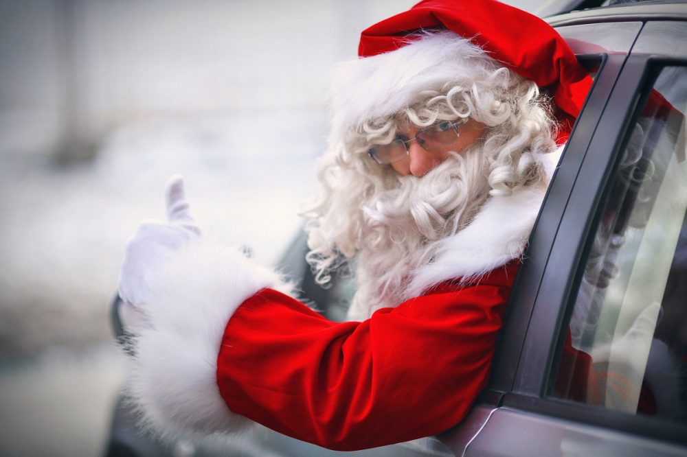 santa driving a car and giving a thumbs up