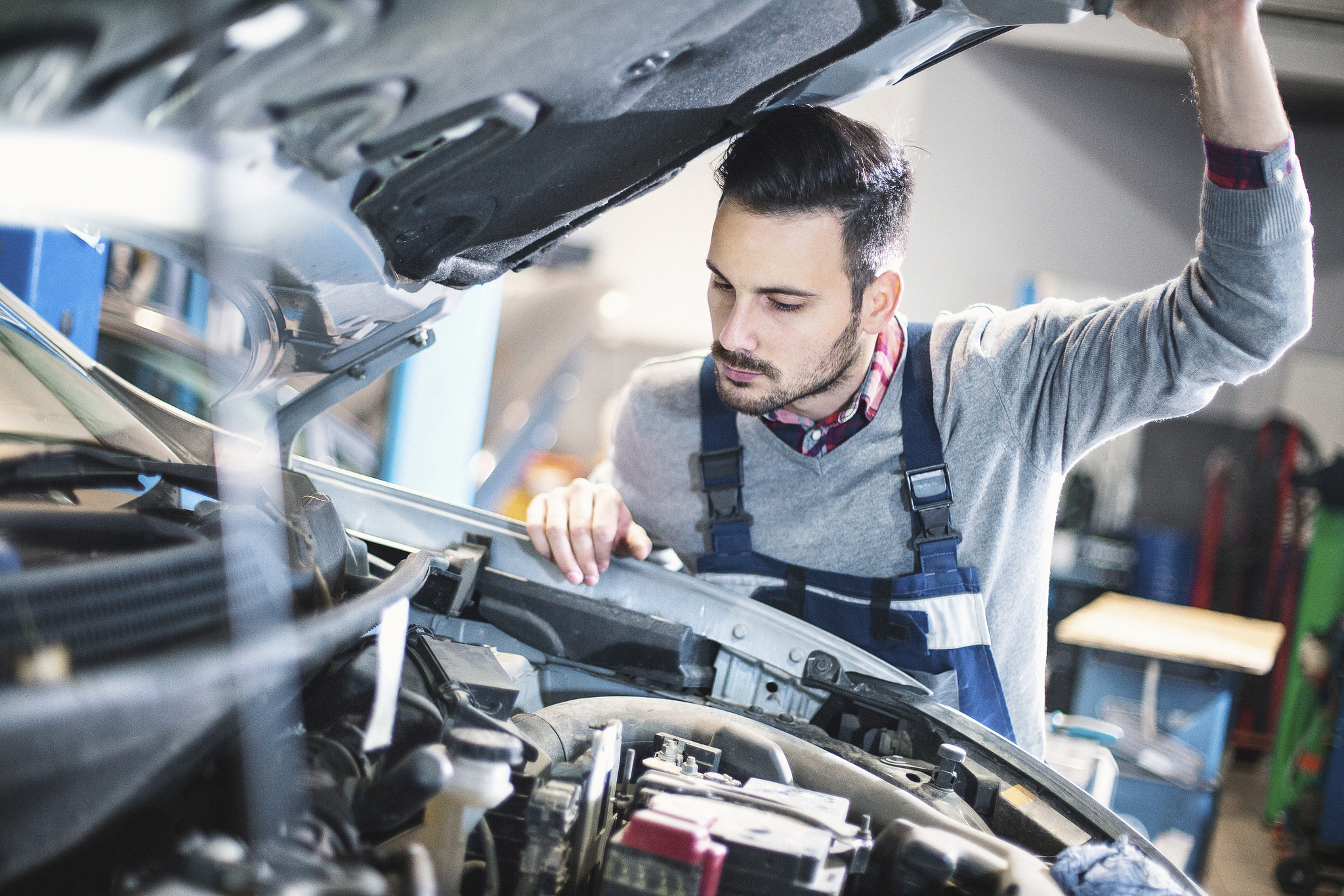 Mechanic fixes. Автомеханик. Чинит автомобиль. Механик автомобилей. Машина в автосервисе.