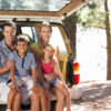 smiling family sitting in back of car