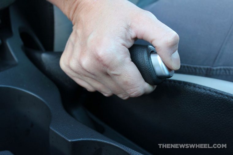 Person engaging emergency or parking brake in a car