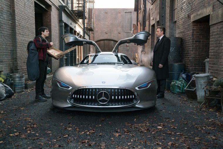 Ben Affleck and Ezra Miller standing on either side of a new Mercedes-Benz in the film Justice League