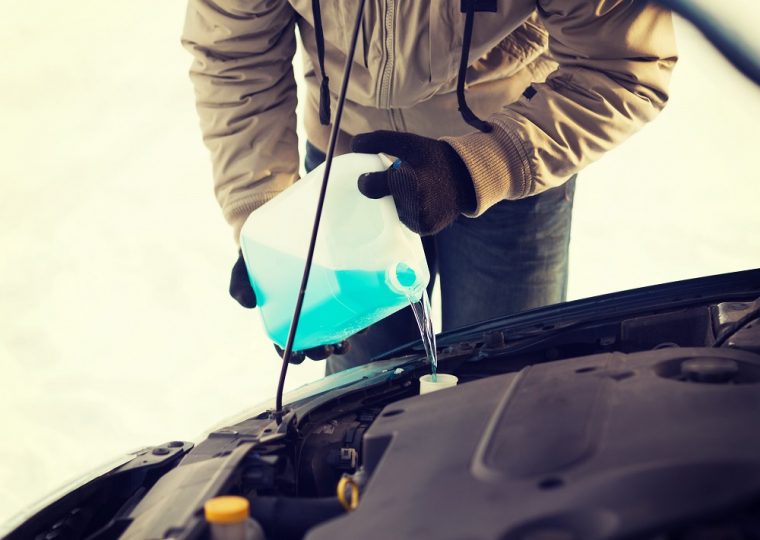 transportation, winter and vehicle concept - closeup of man pouring antifreeze into windscreen water tank