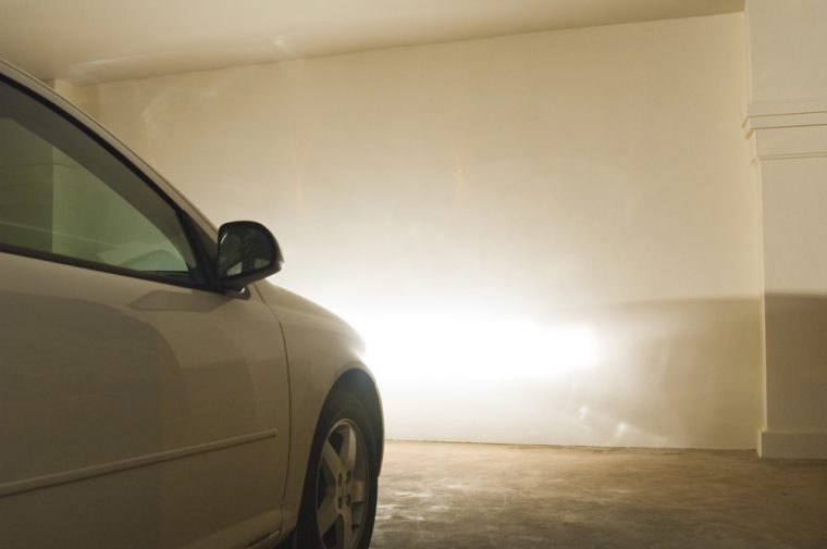 car parked inside a garage with its headlights on