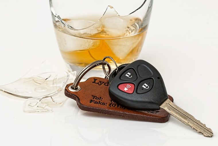 broken glass filled with ice and whiskey with a car key lying on the surface next to it 