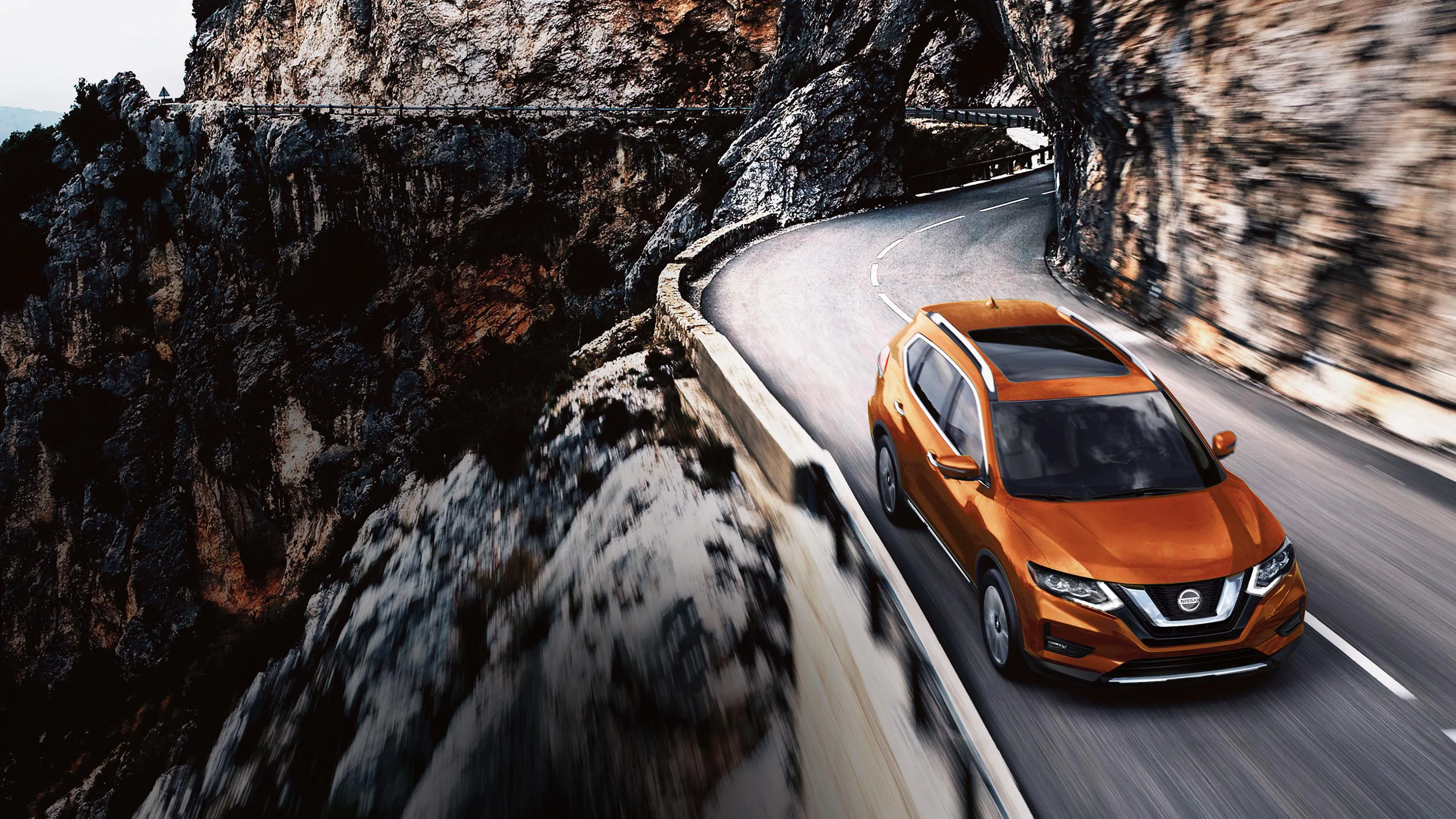 orange 2020 Nissan Rogue driving on a cliffside road