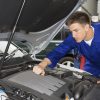 mechanic working under car hood engine