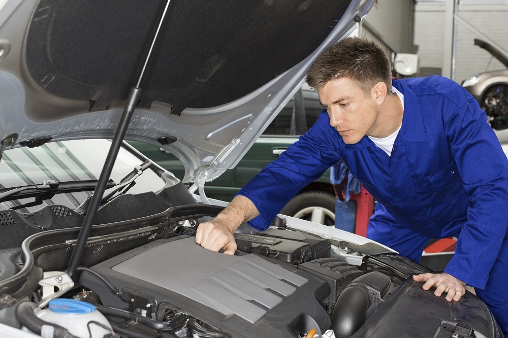 mechanic working under car hood looking at engine