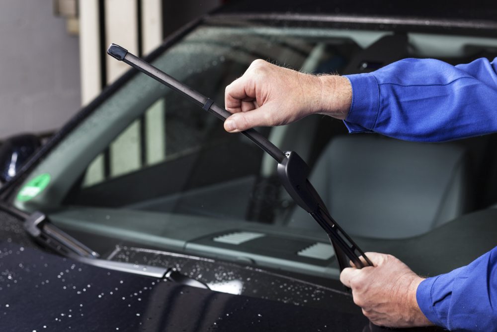 Person checking a windshield wiper on a car