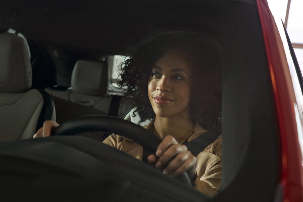 woman sitting in car driver's seat holding steering wheel