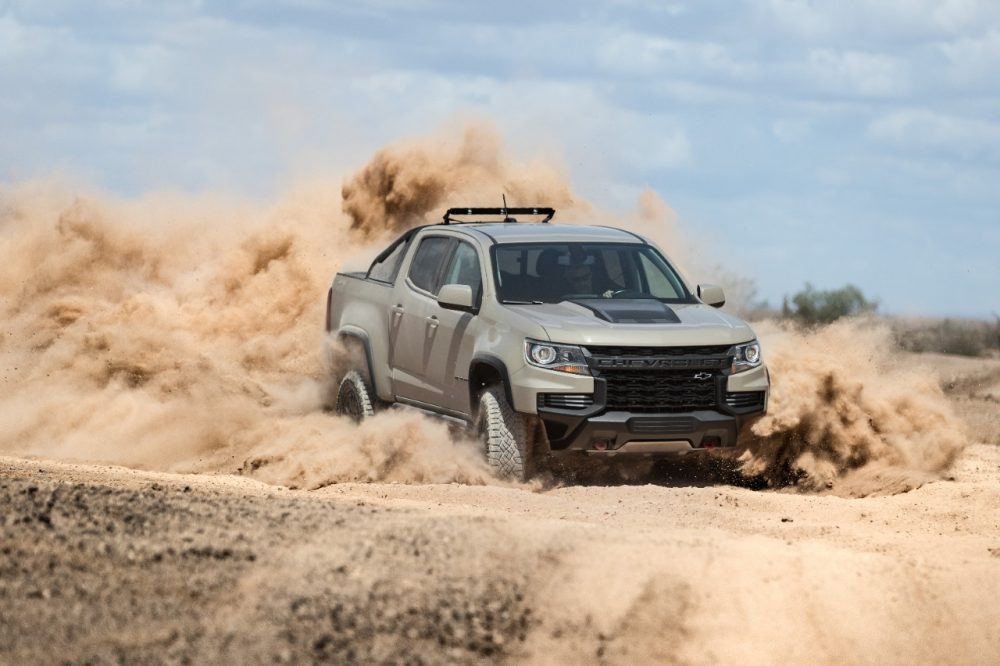 Front side view of 2021 Chevrolet Colorado ZR2 driving off-road in cloud of dirt