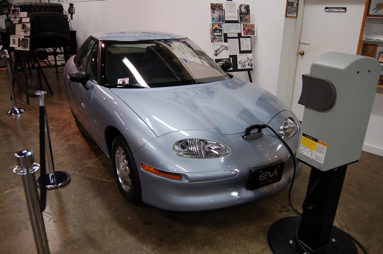 A gray GM EV1 at a charging station