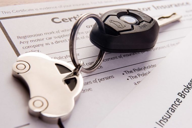 set of car keys sitting on an auto insurance policy. 