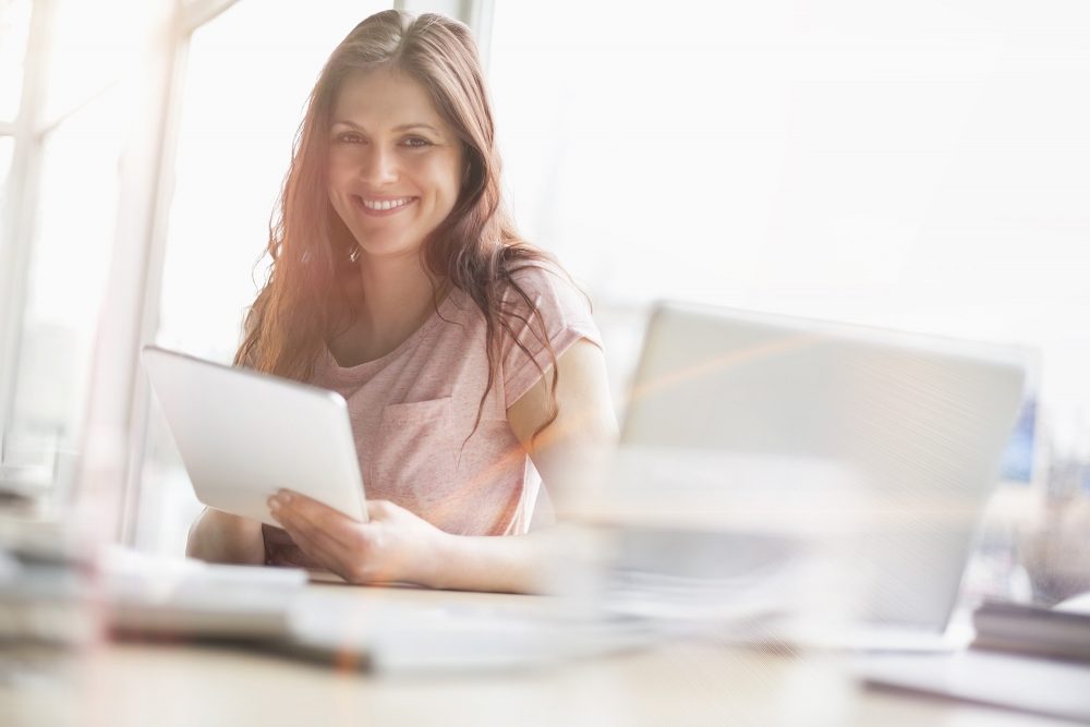 Brunet woan using her laptop and tablet to find the best APR interest rate on a car loan.